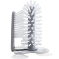 Grey 2 in 1 cup scrubber with double-sided bristles and three suction cups on the base for cleaning glassware.