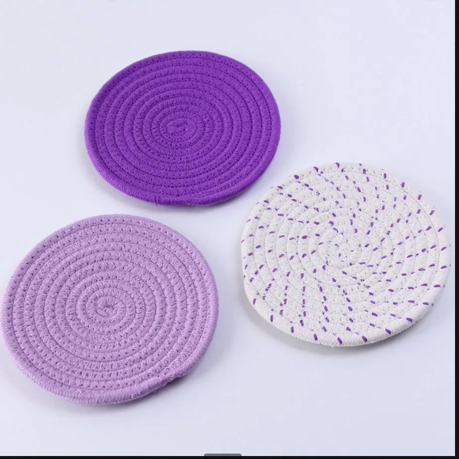 Set of three round cotton cord coasters in blue colour, 18cm diameter, on a table.