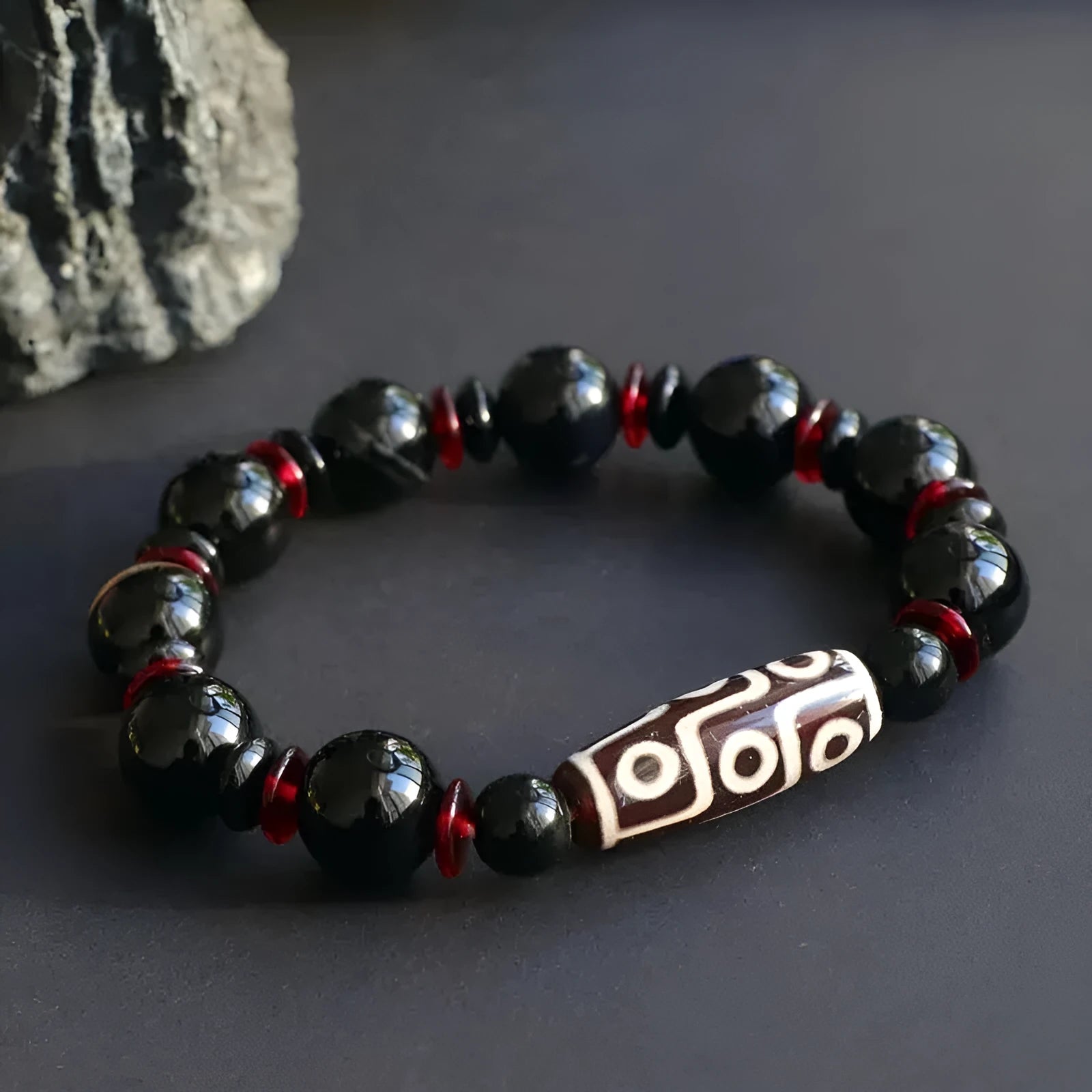 Hand-woven black agate dzi bead bracelet with 11mm geometric beads on a wrist.