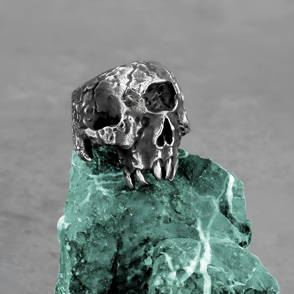Close-up of a silver-toned alloy ring featuring a detailed one-eyed skull design on a black background.