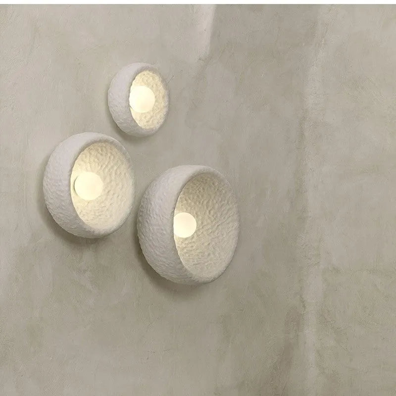 Japanese minimalist wall lamp in resin with warm light, showing three size options