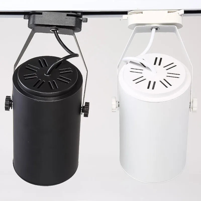 A black aluminium LED track spotlight mounted on a lighting track, angled to illuminate a wall.