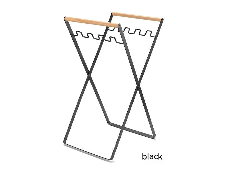 Black foldable outdoor iron trash rack with wooden handle holding a white bin bag.
