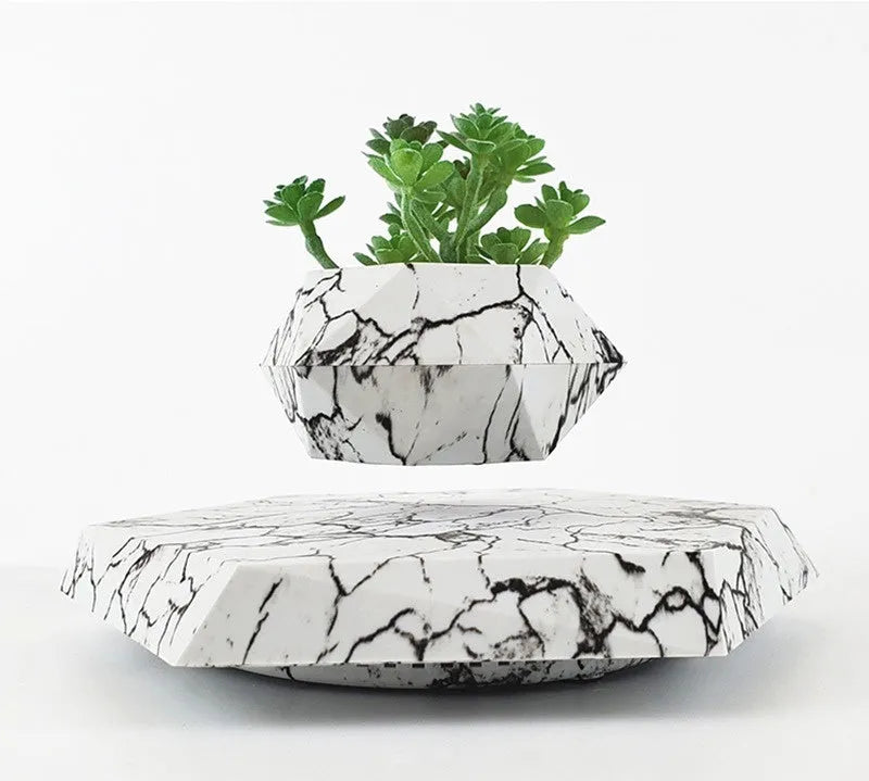 Magnetic levitating marble-colour plant pot floating above base with small plant