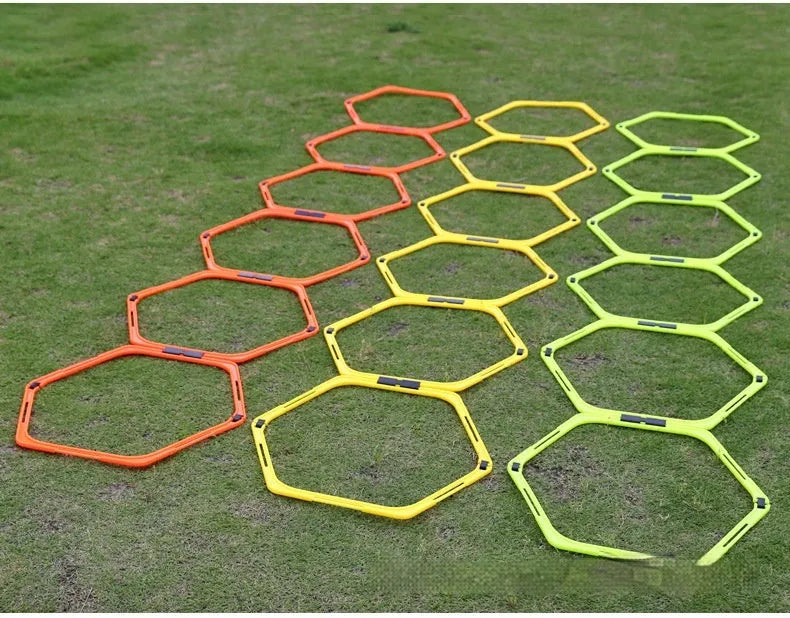 Set of six foldable yellow, green, and orange plastic hexagon football agility training rings laid out on grass.