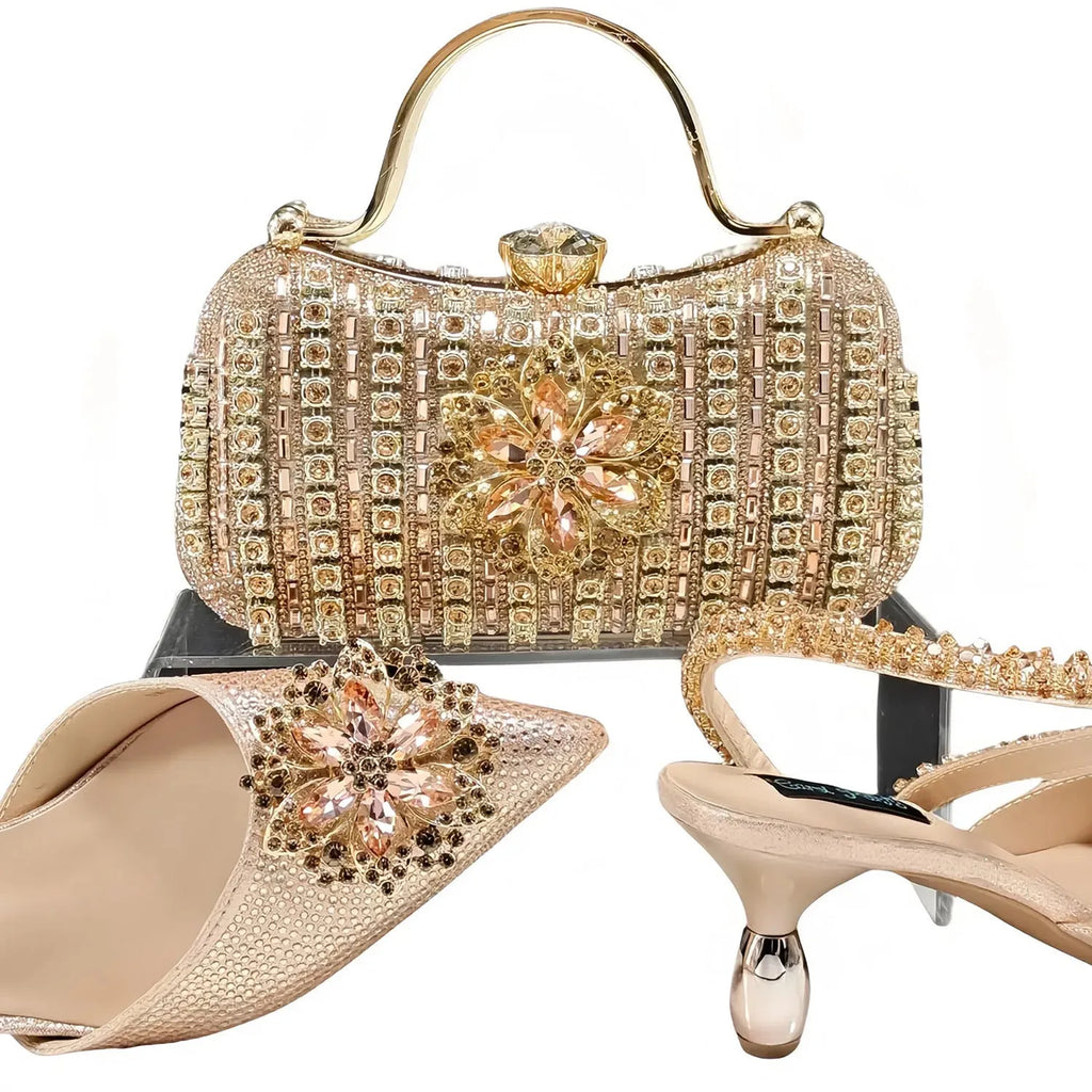 Women's black high heel sandal with rhinestone flower decoration and ankle chain, shown with matching clutch bag