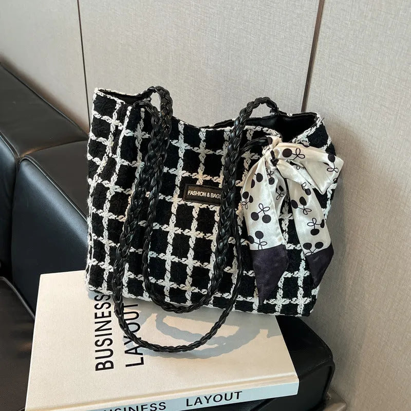 Black woven wool shoulder bag showing horizontal square shape and external pocket.