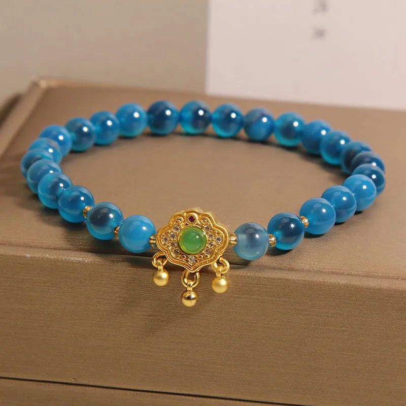 Close-up of a women's bracelet with a blue sugar heart agate safety lock pendant, crystal links, and rhinestone details.
