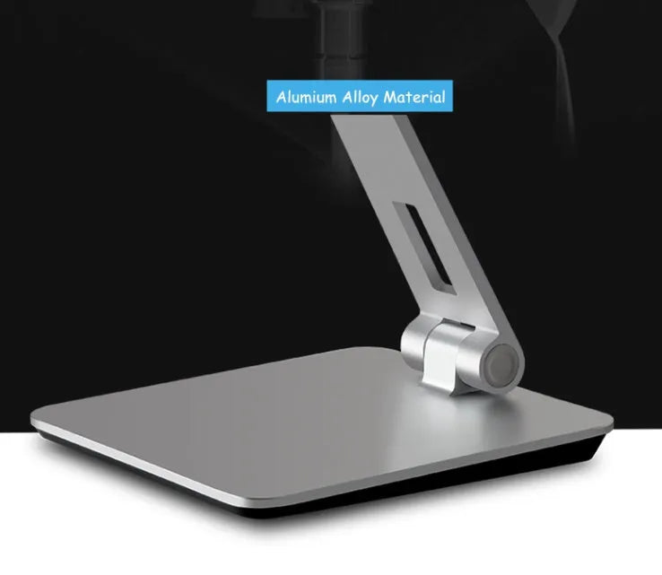 Silver foldable aluminium phone and tablet holder on a desk, showing 360-degree rotation feature.