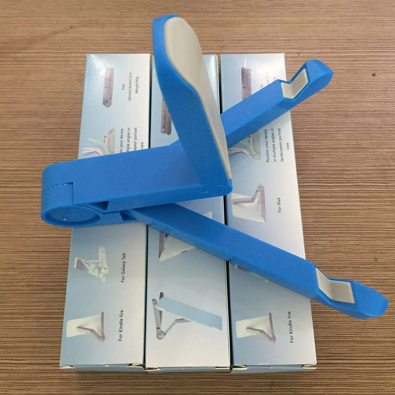 Black foldable tablet holder displaying smartphone at adjustable angle on desk