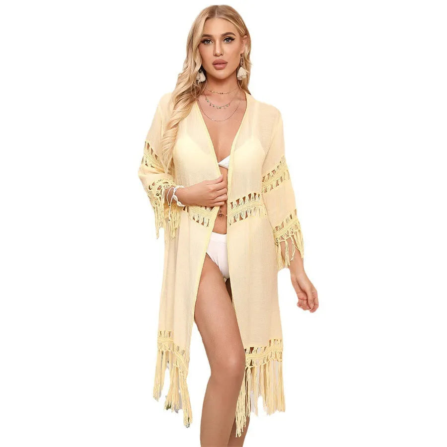 Yellow hand-crocheted women's cardigan with tassel stitching, laid flat as a beach cover-up.