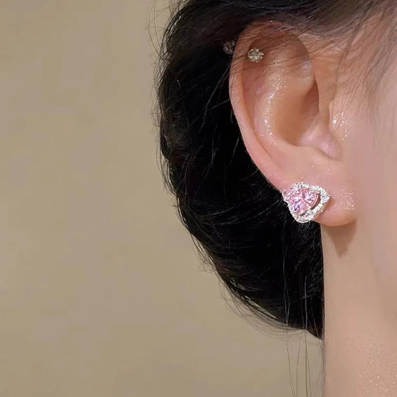 A pair of white heart-shaped stud earrings for women on a plain background.
