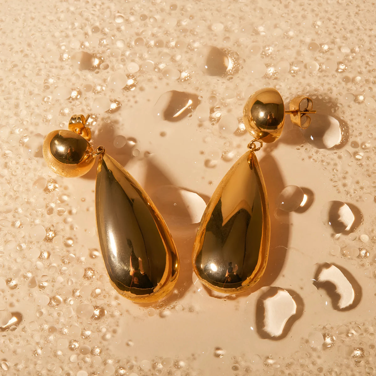 Gold electroplated stainless steel earrings with geometric water drop pendant and hemisphere design