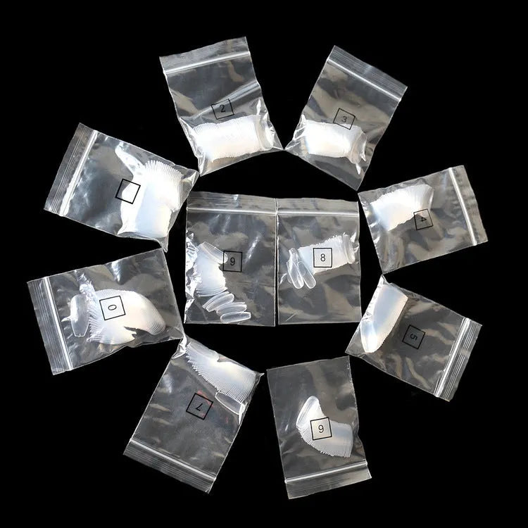 500 clear and natural ABS acrylic false nails in 10 sizes spread on a table