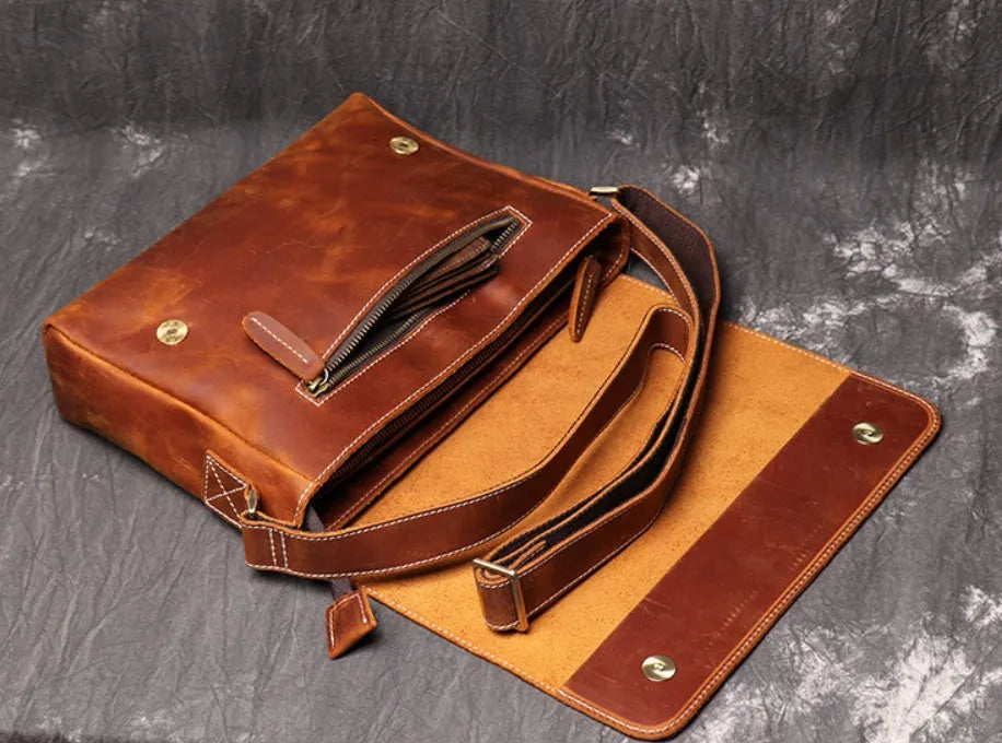 Vintage brown leather men's messenger bag with shoulder strap showing internal organiser pockets.