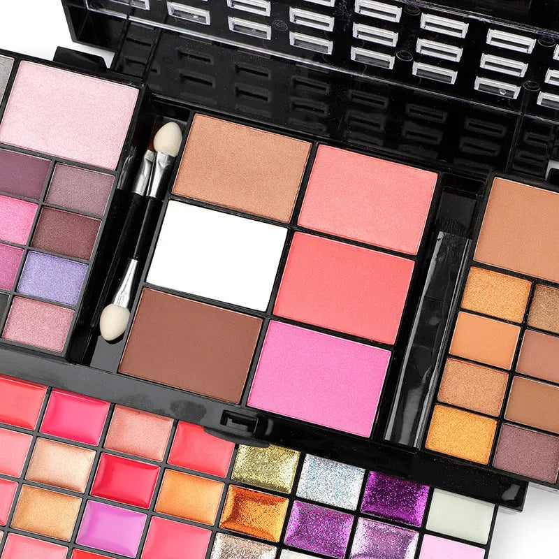 74 colour makeup palette open showing eyeshadows, lip glosses, and face powders with a mirror and brushes.
