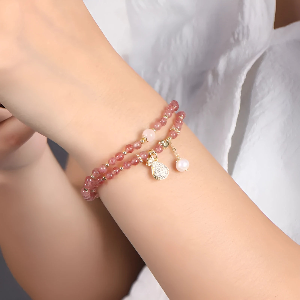 Close-up of a women's geometric bracelet made from pink strawberry quartz crystals.