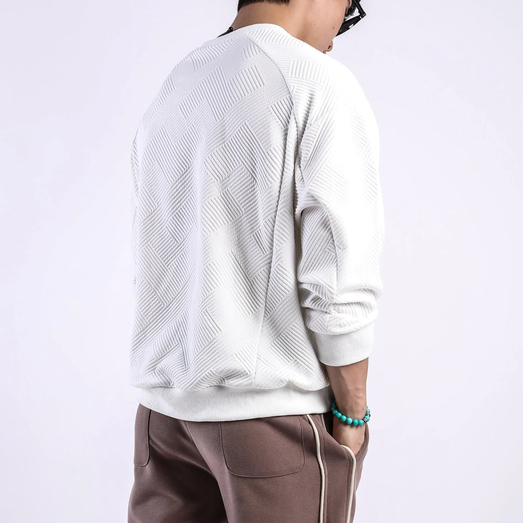 Man wearing a loose-fitting, long-sleeved army green pullover sweater with a textured twill jacquard pattern.
