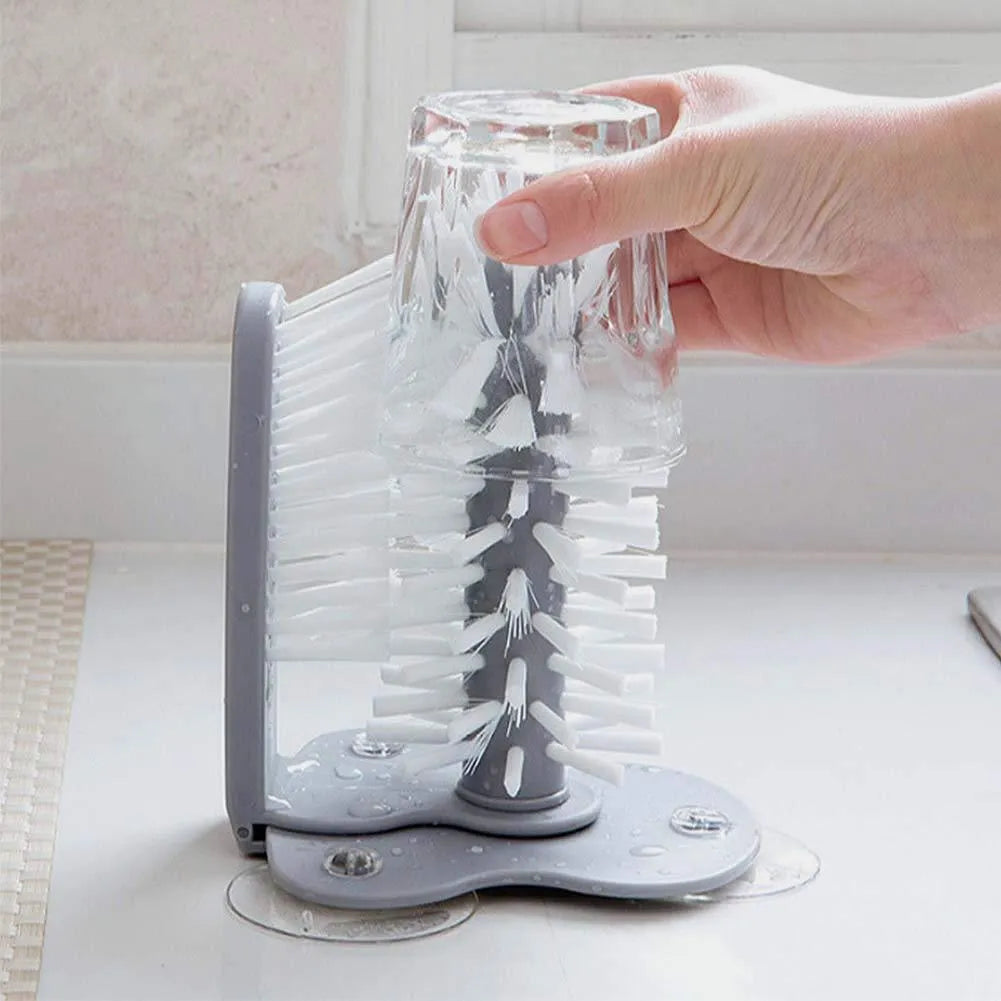 Grey 2 in 1 cup scrubber with double-sided bristles and three suction cups on the base for cleaning glassware.