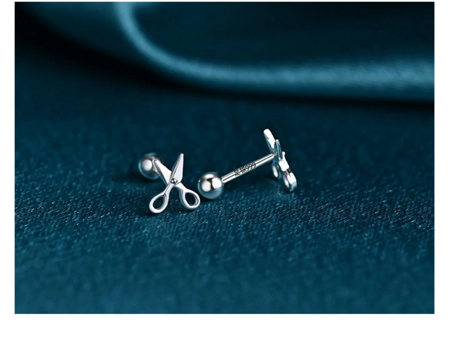 A pair of silver screw-back ear nails with a miniature scissors design on the screw component.