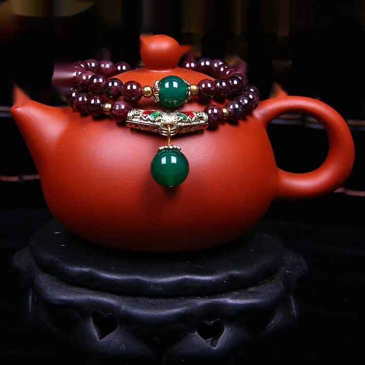 Red garnet bracelet with 7mm beads and a golden toad charm on wrist.