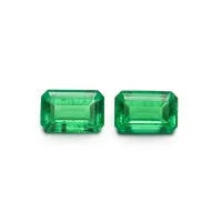 Cultivated emerald loose gemstones in round and fancy cut shapes on a dark background.