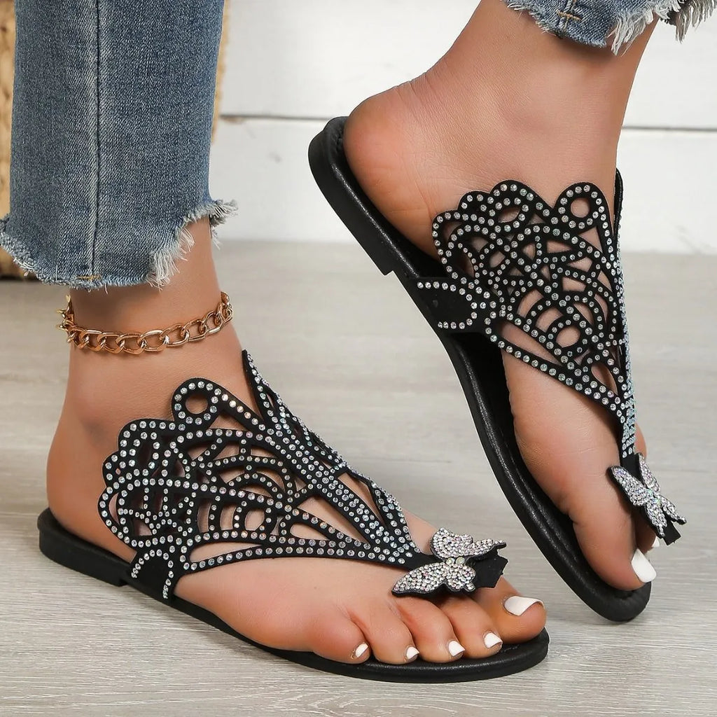 Women's black slip-on sandals with rhinestone detail and flip-toe design on a rubber sole.