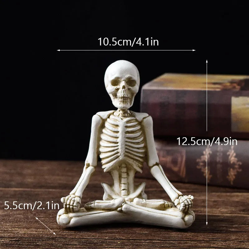 Detailed resin Halloween ornament of a yoga-posing skeleton skull on a desktop.