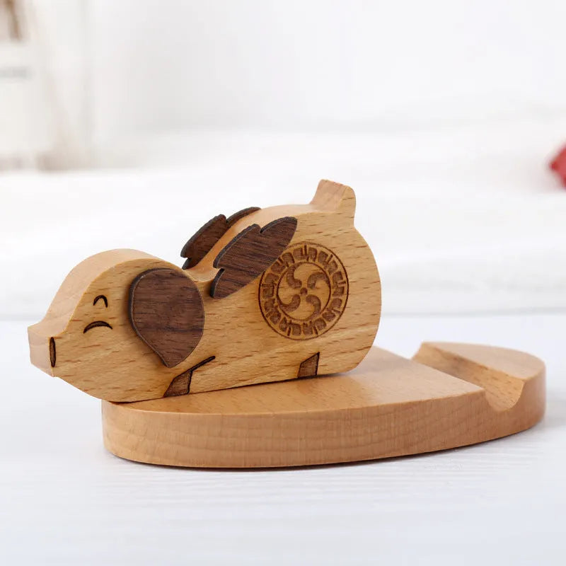 Solid beech wood mobile phone stand with a decorative resin animal ornament and a coin slot.