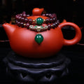 Red garnet bracelet with 7mm beads and a golden toad charm on wrist.