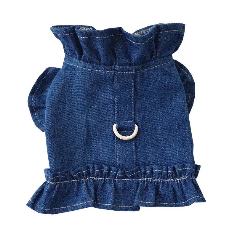 Blue denim vest dress for dog with ruffle trim and metal leash hook on chest.