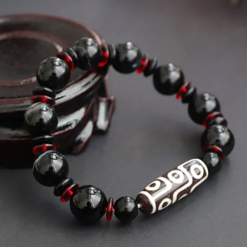 Hand-woven black agate dzi bead bracelet with 11mm geometric beads on a wrist.