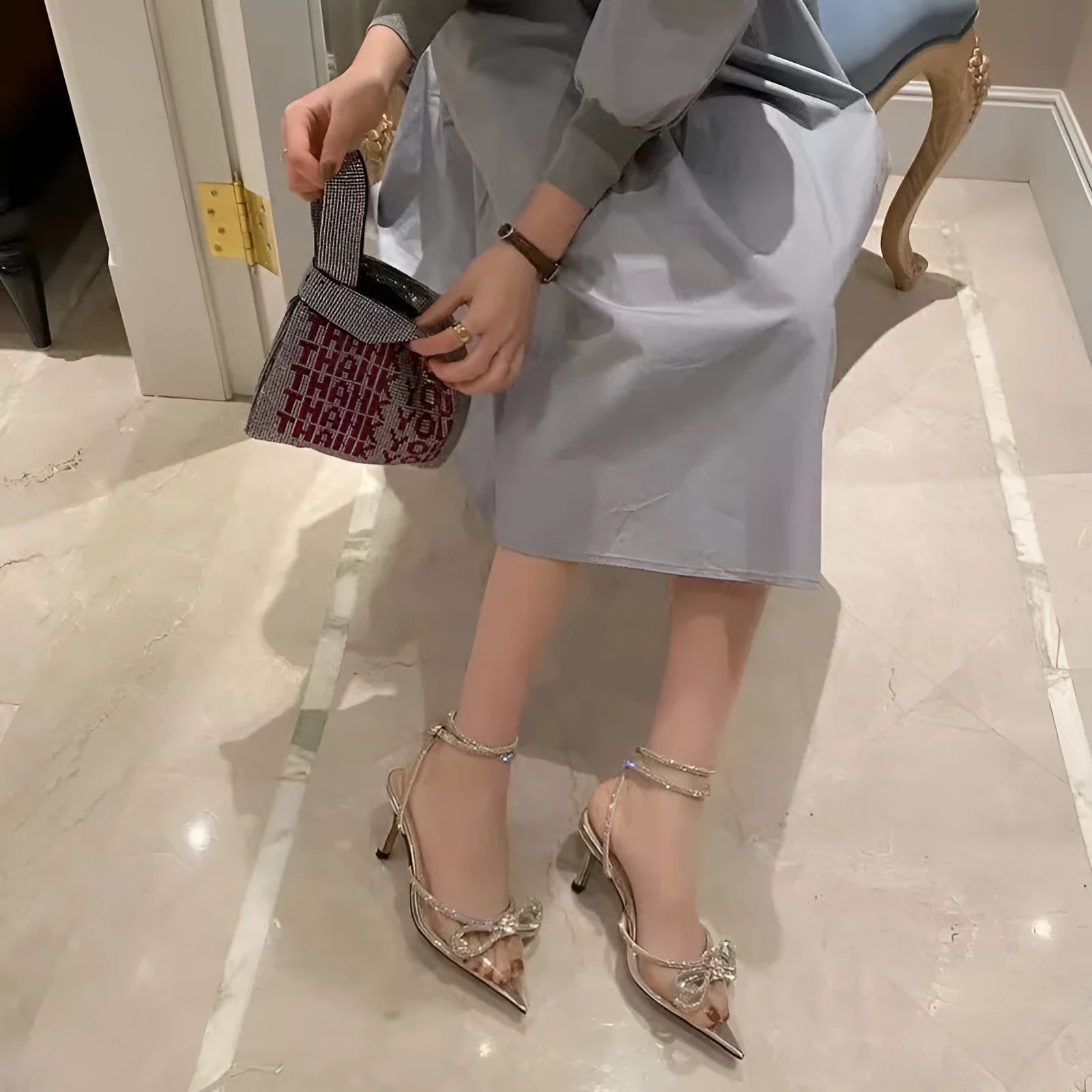 Women's black stiletto heel sandals with a silk back bandage and pointed toe, showing buckle fastening.