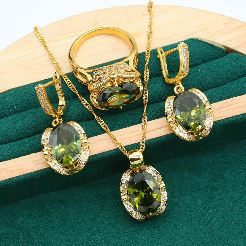 Olive green zircon stone jewellery set with cross, crown, and roman numerals pendant on a snake bones chain, plus matching earrings and ring.