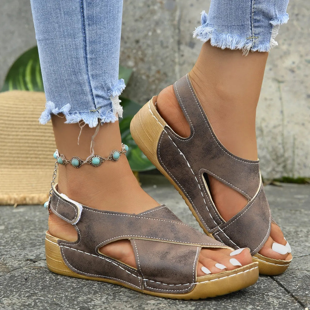 Women's brown Roman sandals with Velcro strap and platform wedge sole on a white background.