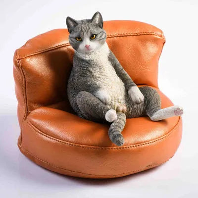 Small resin ornament of a cat sleeping on a sofa for car dashboard or shelf decoration.