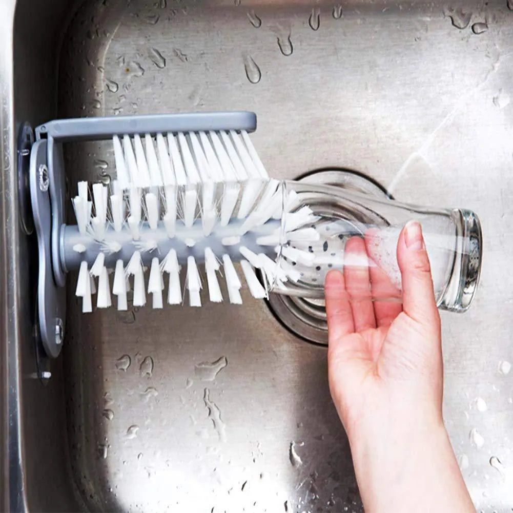 Grey 2 in 1 cup scrubber with double-sided bristles and three suction cups on the base for cleaning glassware.