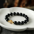 Unisex geometric bracelet with black obsidian, white crystal beads, and a golden dragon bead on a wrist.