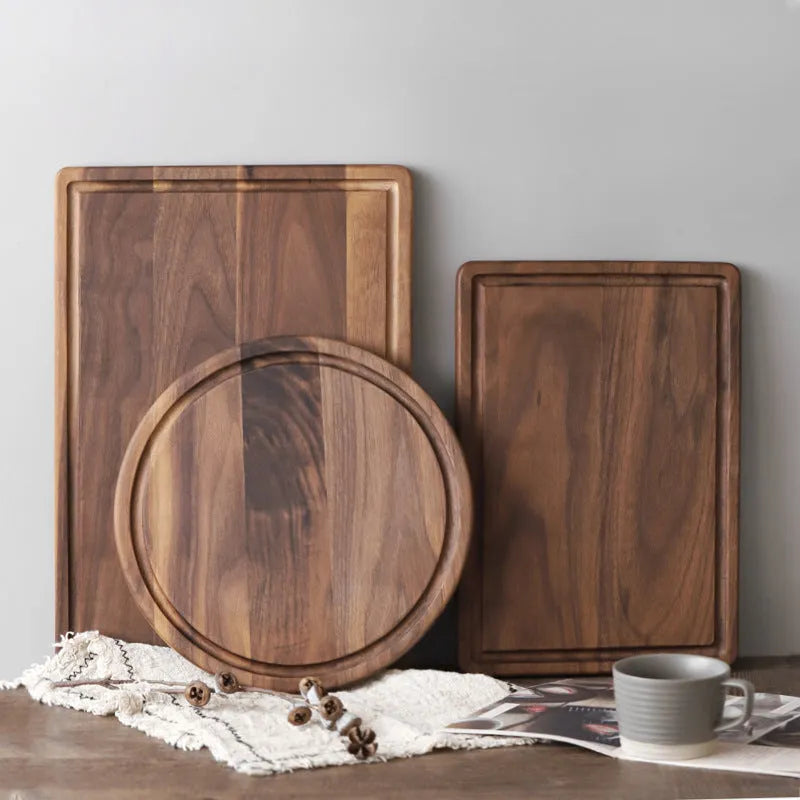 Black walnut wood cutting board with juice groove and side handle, shown in round and rectangular sizes.