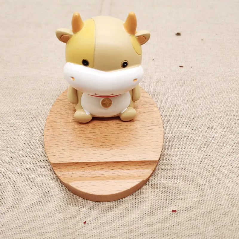 Solid beech wood mobile phone stand with a decorative resin animal ornament and a coin slot.