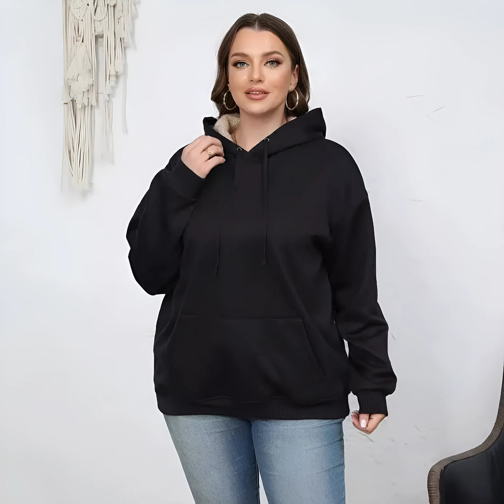 Woman wearing a loose black hooded sweater with a raised 3D pattern on the fabric.