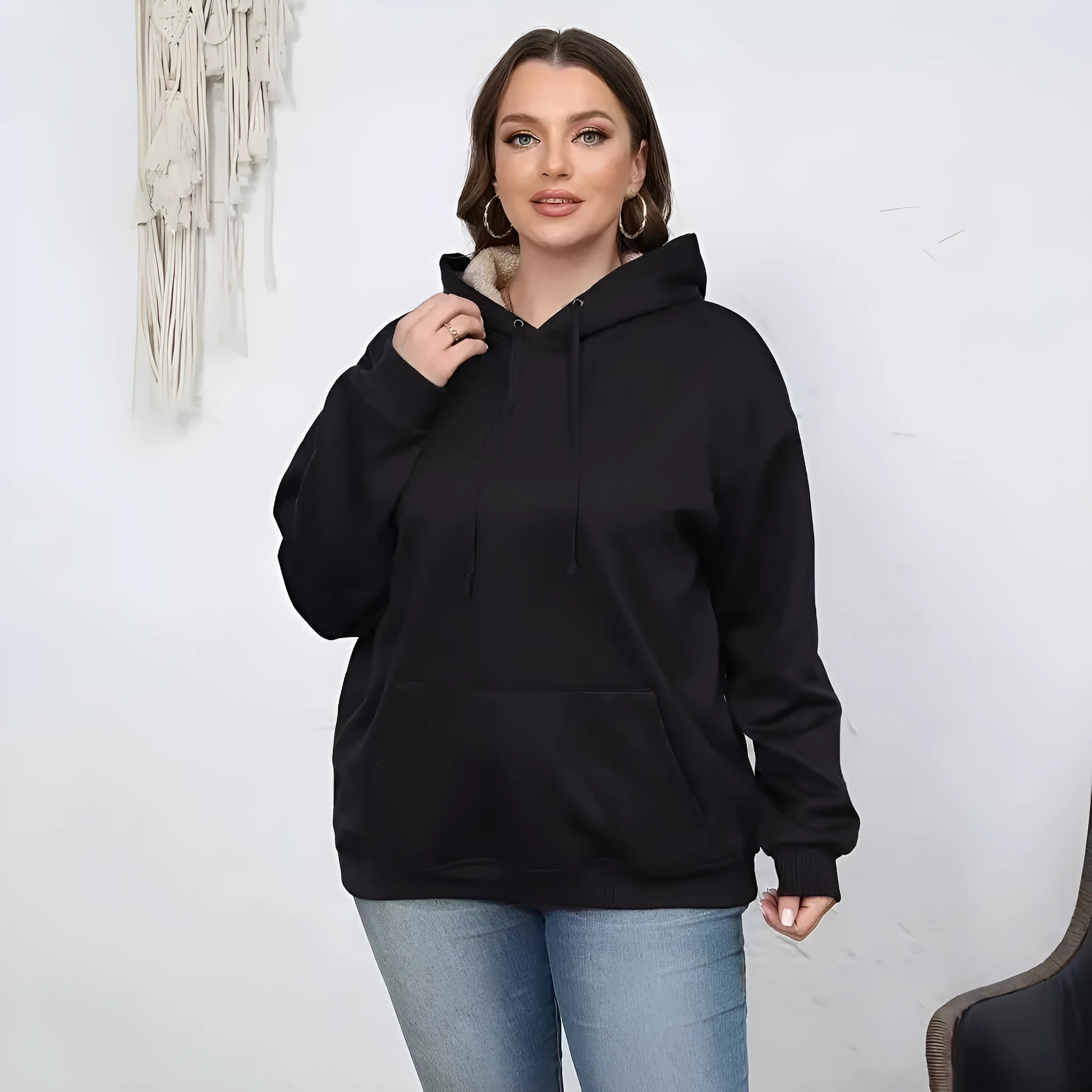 Woman wearing a loose black hooded sweater with a raised 3D pattern on the fabric.