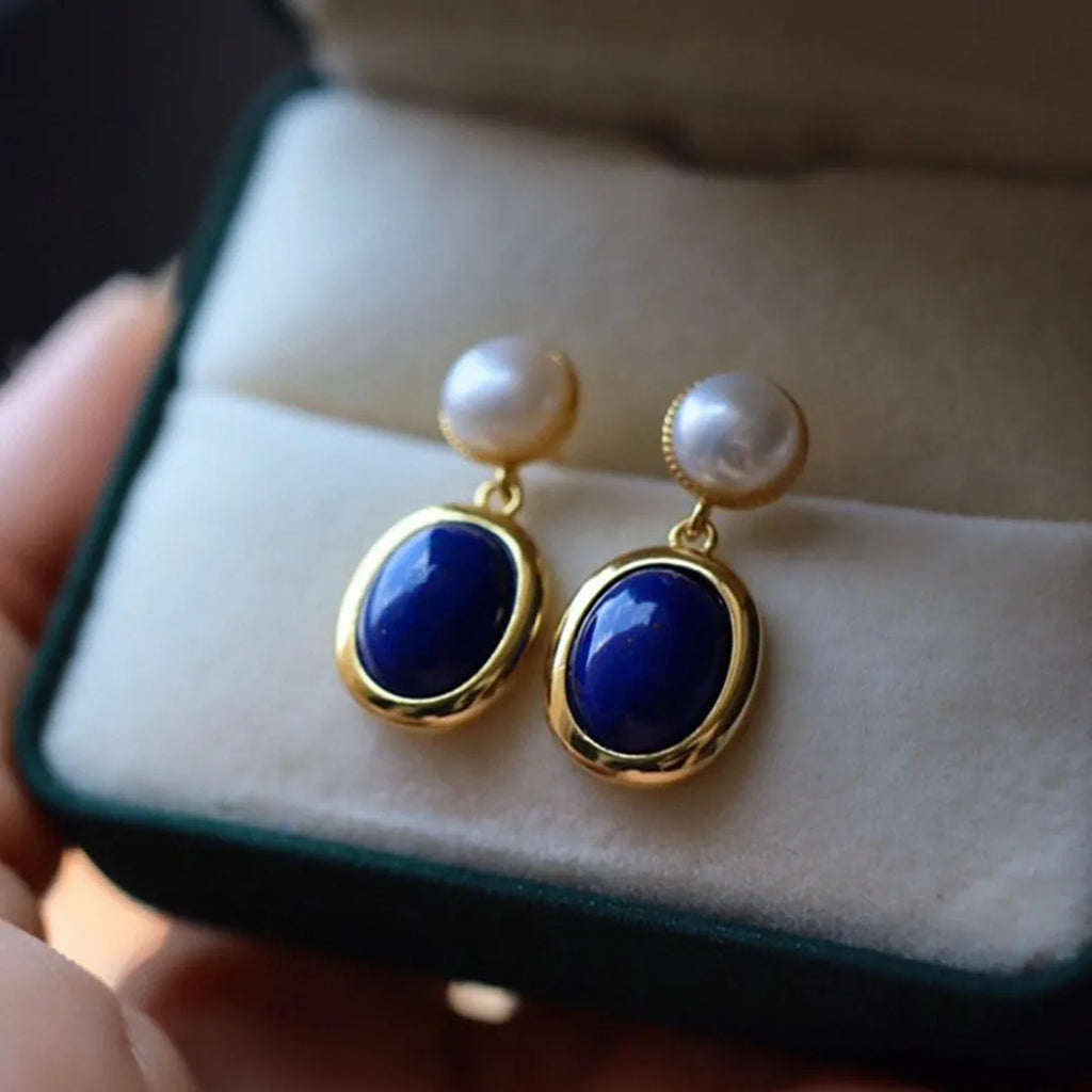 A pair of simple sterling silver earrings featuring blue lapis lazuli pearls and auspicious pattern detailing.
