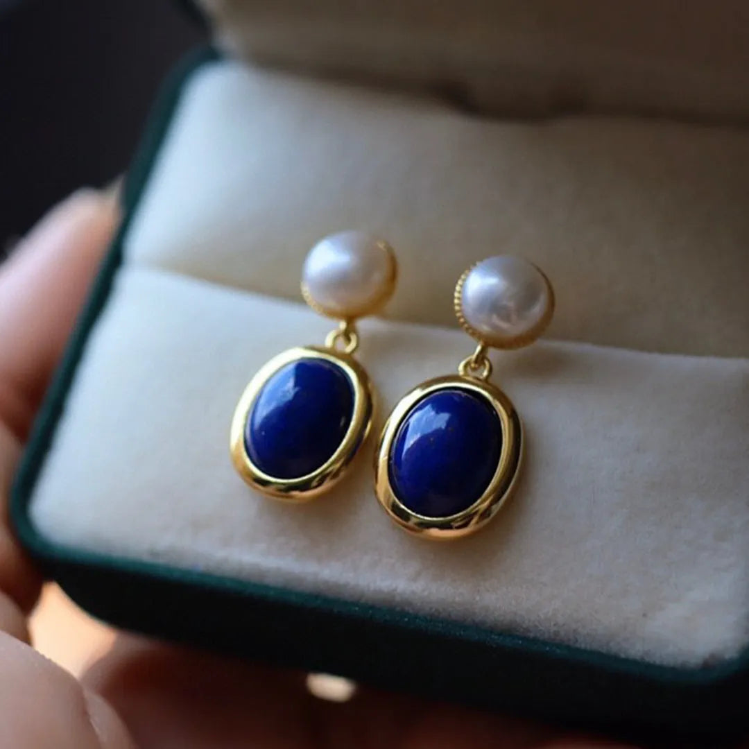 A pair of simple sterling silver earrings featuring blue lapis lazuli pearls and auspicious pattern detailing.