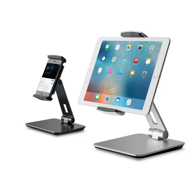 Silver foldable aluminium phone and tablet holder on a desk, showing 360-degree rotation feature.