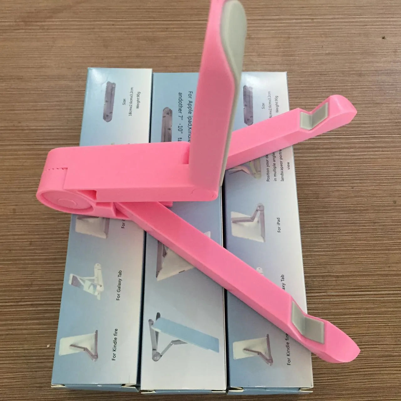 Black foldable tablet holder displaying smartphone at adjustable angle on desk