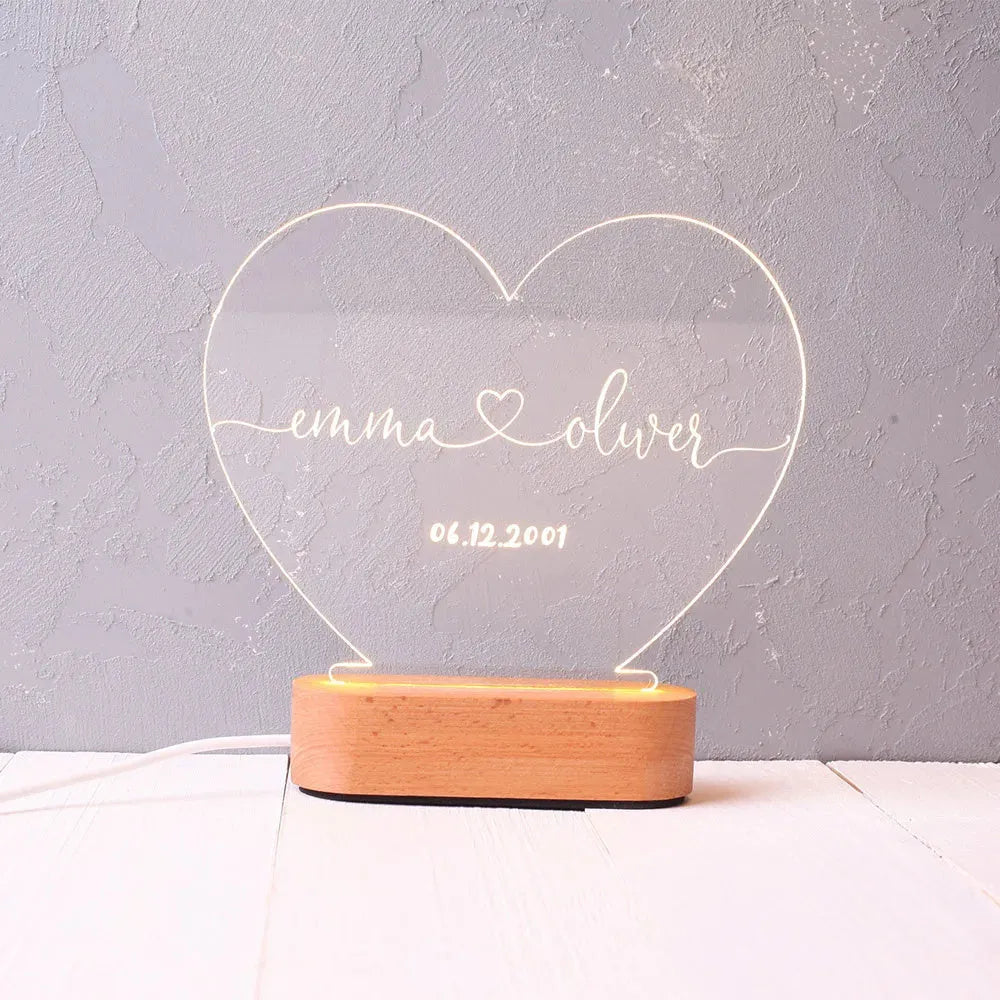 Personalised acrylic night light showing illuminated custom names and date on a transparent panel.