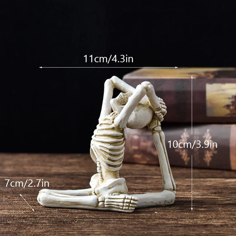 Detailed resin Halloween ornament of a yoga-posing skeleton skull on a desktop.