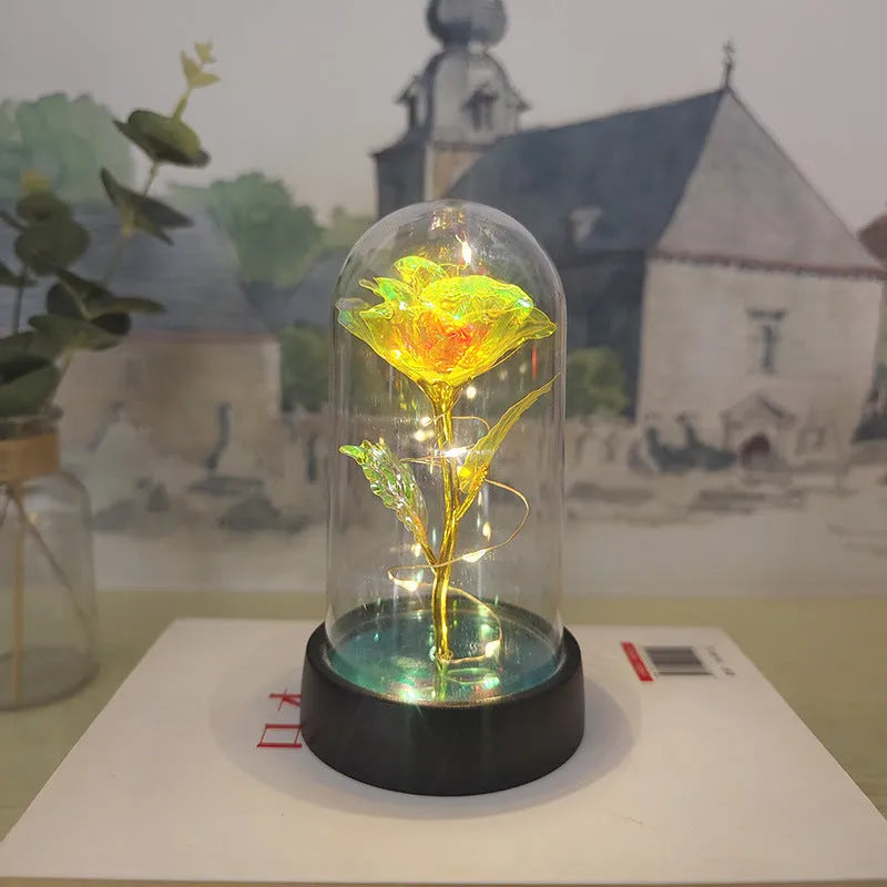 Small glass night lamp with plastic flowers on a black base.