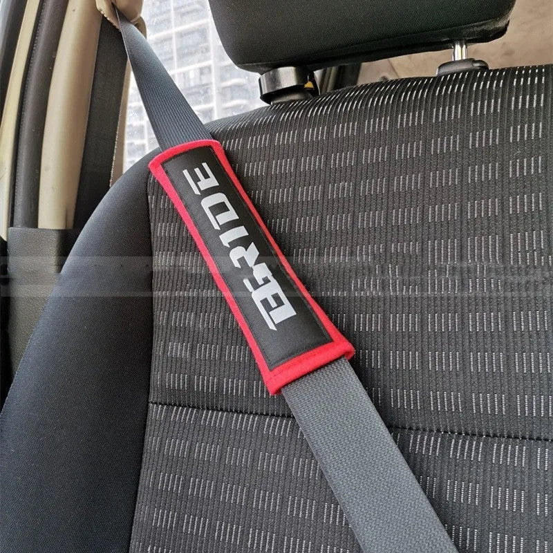 Pair of black car seat belt shoulder pads made from cotton sponge cloth, showing embroidery detail.